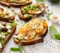 Assorted open faced sandwiches, in the middle of board an open avocado sandwich made of slice of sourdough bread with the addition