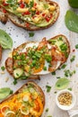 Assorted open faced sandwiches, Open avocado sandwiches made of slices of sourdough bread with various toppings on a white wooden