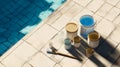 Assorted paint cans, brush, and containers on tiled surface beside blue pool. Royalty Free Stock Photo