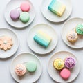 Assorted pastel-colored desserts are arranged on white plates Royalty Free Stock Photo