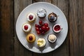 Assorted petite desserts presented on white plate, adorned with cherries