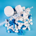 Assorted pharmaceutical medicine pills, tablets and capsules in bottle, syringe on blue background Royalty Free Stock Photo