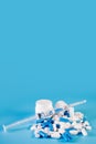 Assorted pharmaceutical medicine pills, tablets and capsules in bottle, syringe on blue background. Royalty Free Stock Photo