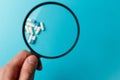 Assorted pharmaceutical medicine pills, tablets and capsules under the magnifying glass on blue background. Top view. Flat lay Royalty Free Stock Photo