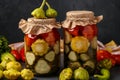 Assorted pickled cucumbers, patissons and tomatoes in jars on a dark background, horizontal orientation Royalty Free Stock Photo