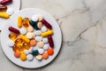 Assorted pills are in a white plate. Different tablets and capsules. Copy space.