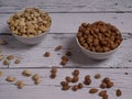 Assorted pistachio nuts, cashews, almonds and hazelnuts in two bowls on a white wooden table