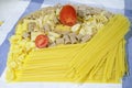 Assorted raw pasta and halved fresh tomato Royalty Free Stock Photo
