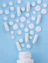 Assorted scattered pharmaceutical medicine pills, tablets and capsules and bottle on blue background. Medicine concept.