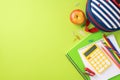 Assorted school supplies on a green background with a striped backpack Royalty Free Stock Photo