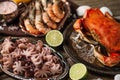 Assorted of seafood on rustic wooden table. Top view of tiger shrimps, cooked crab and baby octopuses served with lime and