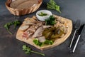 Assorted sliced delicious meat mix as salami, bacon and ham with pickles, lard and bread on a wooden cutting board on grey cement Royalty Free Stock Photo