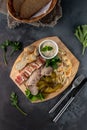 Assorted sliced delicious meat mix as salami, bacon and ham with pickles, lard and bread on a wooden cutting board on grey cement Royalty Free Stock Photo