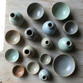 Assorted small ceramic bowls and vases are arranged on a wooden surface Royalty Free Stock Photo