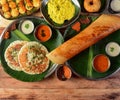 Assorted South indian breakfast foods on wooden background. Ghee dosa, uttappam,medhu vada,pongal,podi idly and chutney.. Dishes