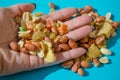 Assorted of sugared dried fruits, nuts and dragees in sugar in open palm, on blue background