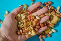 Assorted of sugared dried fruits, nuts and dragees in sugar in open palm, on blue background