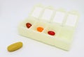 Assorted Supplement Pills in Daily Pill Organizer Case with One of Them at the Outside