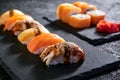 Assorted sushi with salmon, eel and escolar on black stone plate on dark background