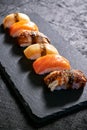 Assorted sushi with salmon, eel and escolar on black stone plate on dark background. Minimal concept