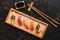 Assorted sushi set on a dark rustic background. Japanese food sushi on a wooden plate, soy sauce, chopsticks. Top view. Sushi Royalty Free Stock Photo