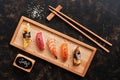 Assorted sushi set on a dark rustic background. Japanese food sushi on a wooden plate, soy sauce, chopsticks. Top view Royalty Free Stock Photo