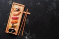 Assorted sushi set on a wooden plate, dark stone background. Japanese food sushi, soy sauce, chopsticks. Top view, copy space Royalty Free Stock Photo