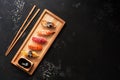 Assorted sushi set on a wooden plate, dark stone background. Japanese food sushi, soy sauce, chopsticks. Top view, copy space Royalty Free Stock Photo