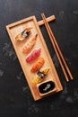 Assorted sushi set on a wooden plate, dark stone background. Asian food sushi, soy sauce, chopsticks. Top view, copy space Royalty Free Stock Photo