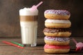 Assorted sweet donuts with icing and toppings, and coffee latte on a brown wooden table Royalty Free Stock Photo