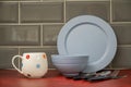 blue pottery china dinner plate bowl with white bone china cup and black handled stainless steel cutlery on a red linoleum work