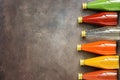 Assorted various colored juices in bottles on a dark background, vertical border. Top view, flat lay. Juice - dragon fruit, orange