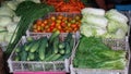 Assorted vegetables in the basket. There are cucumbers, tomatoes, mustard greens, chicory, long beans