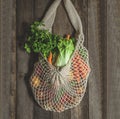 Assorted vegetables in mesh grocery bag isolated on wooden background Royalty Free Stock Photo