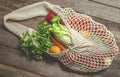 Assorted vegetables in mesh grocery bag isolated on wooden background Royalty Free Stock Photo