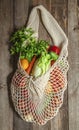 Assorted vegetables in mesh grocery bag isolated on wooden background Royalty Free Stock Photo