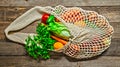 Assorted vegetables in mesh grocery bag isolated on wooden background Royalty Free Stock Photo