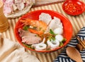 Assorted vegetarian and seafood Soup in a bowl with spoon and chopsticks isolated on mat side view on wooden table taiwan food