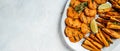 Assortment of baked sweet potatoes fries with lime and herbs on plate, on light background. Long banner format. top view Royalty Free Stock Photo