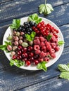 Assortment of berries - raspberries, gooseberries, red currants, cherries, black currants on a white plate on a wooden background. Royalty Free Stock Photo