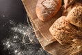 Assortment of bread on sackcloth and flour on black table