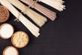 Assortment of bundles raw noodles with ingredient in wooden bowls on black striped mat background with copy space, top view. Royalty Free Stock Photo