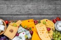 Assortment cheeses on wooden cutting board. Cheese plate served with grape fruits, tomatoes and rosemary, various cheese Royalty Free Stock Photo