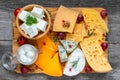 Assortment cheeses on wooden cutting board. Cheese plate served with grape fruits, tomatoes and rosemary, various cheese Royalty Free Stock Photo