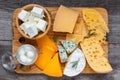 Assortment cheeses on wooden cutting board. Cheese plate served with rosemary, various cheese on a platter. top view Royalty Free Stock Photo