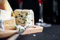 Assortment of cheeses on a wooden plate and two wine glasses. Royalty Free Stock Photo