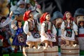 Assortment of clay Souvenirs in traditional moldovan suits. Souvenir clay figurines of women trample grapes in wooden skating