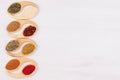 Assortment colorful powdered spices in bamboo spoons as decorative border.