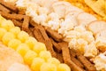 Assortment crunchy snacks - popcorn, nachos, croutons, corn sticks, potato chips as decorative stripes background, closeup.