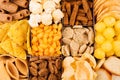 Assortment crunchy snacks - popcorn, nachos, croutons, corn sticks, potato chips in cells as decorative background, top view, clos